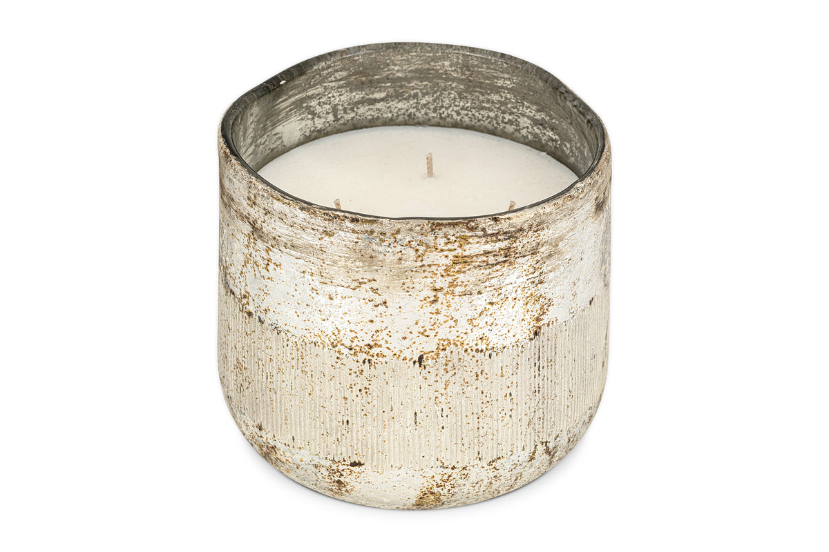 The nkuku Juniper & Fir 3 Wick Scented Candle features a rustic, weathered silver container with a textured finish and uneven rim, creating an inviting atmosphere with its bespoke fragrance.