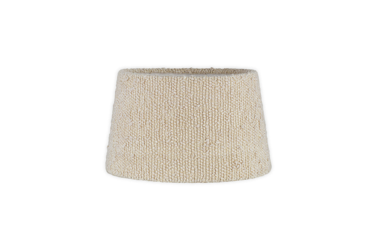 The Sakiti Bouclé Lampshade by nkuku features an off-white, cone-shaped woven fabric design with a classic tapered silhouette, ideal for ambient lighting. Displayed against a plain white background.