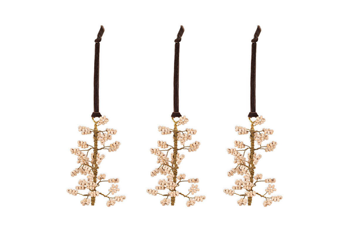 The nkuku Tanu Mango Wood Beaded Baubles – Brass & Natural (Set of 3) feature gold-toned branches with pale pink beads and hang from dark brown ribbons. They make elegant festive table decor.