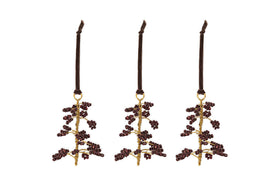 The nkuku Tanu Mango Wood Beaded Baubles - Brass & Ruby (Set of 3) feature gold stems and ruby beads, each hanging from a dark brown velvet ribbon. Unique Christmas tree decorations to brighten your festive décor.