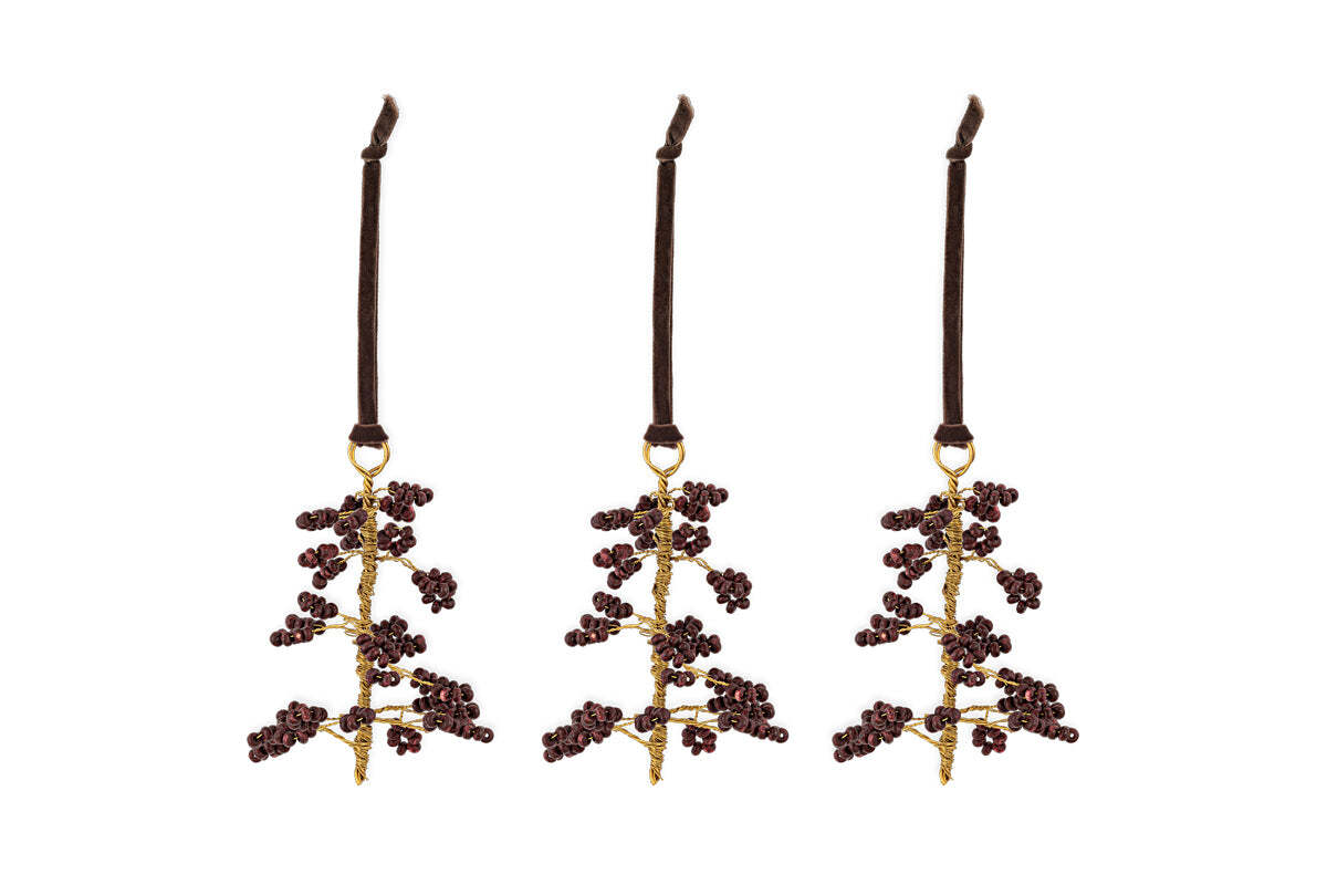 The nkuku Tanu Mango Wood Beaded Baubles - Brass & Ruby (Set of 3) feature gold stems and ruby beads, each hanging from a dark brown velvet ribbon. Unique Christmas tree decorations to brighten your festive décor.