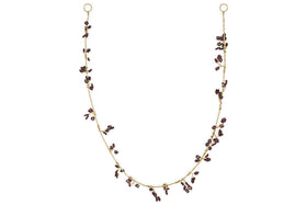 The nkuku Tanu Mango Wood Beaded Garland features brass and ruby beads, artfully clustered along the strand for a whimsical, foliage-inspired look. Displayed in a gentle U shape against a plain white background.