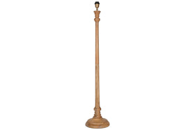 The Usha Classic Wooden Floor Lamp - Natural by nkuku is a tall, handmade mango wood base with a natural finish, round sturdy bottom, and ornately carved slender pole. Eco-friendly, it comes without a lampshade or bulb. Background is white.