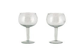 Two clear Yala Hammered Gin Glasses by nkuku, featuring round bowls and long stems, are displayed side by side on a white background. Set of 2.