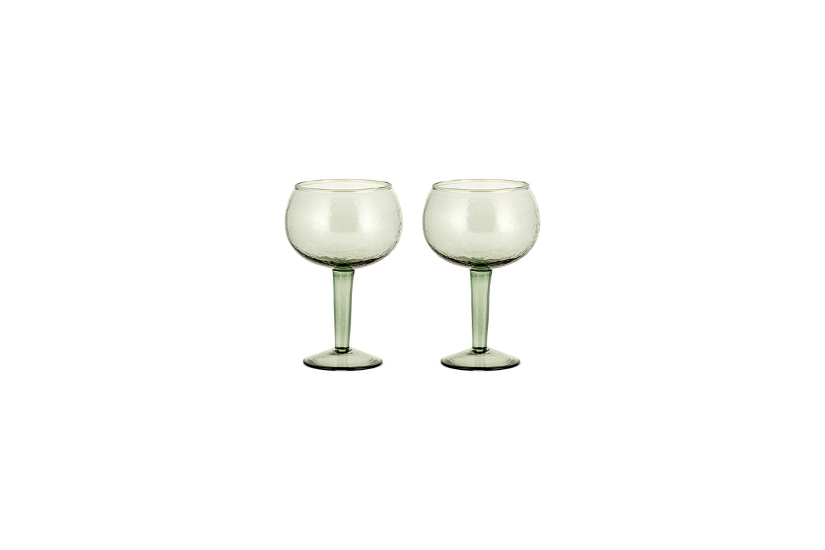 The nkuku Yala Hammered Gin Glass set includes two sage green glasses with long stems, displayed side by side on a white background.