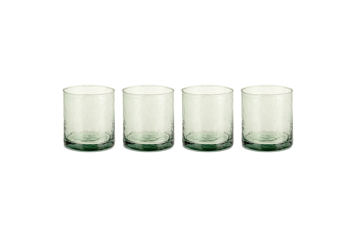 The nkuku Yala Hammered Tumbler - Sage Green (Set of 4) features clear, textured recycled glass tumblers with a subtle sage green tint at the base, shown side by side on a white background.