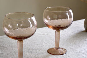 A set of two nkuku Yala Hammered Gin Glasses in Dusty Terracotta sits on a light tablecloth against a neutral background.