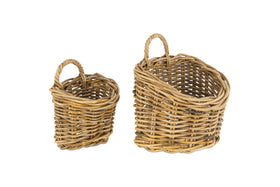 The Zawar Rattan Hanging Baskets - Natural (Set of 2) by nkuku sit side by side on a white background; both oval-shaped with twisted handles, their sturdy, rustic design comes in small and large sizes—ideal for pantry storage.