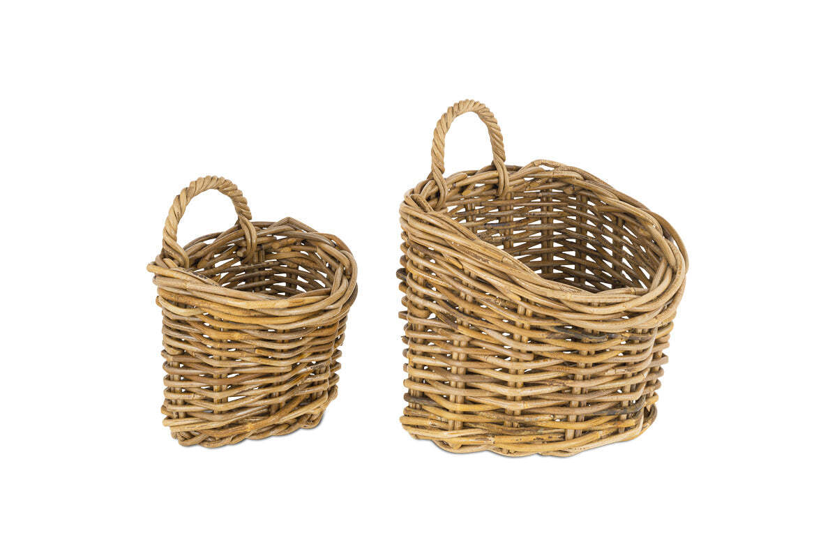 The Zawar Rattan Hanging Baskets - Natural (Set of 2) by nkuku sit side by side on a white background; both oval-shaped with twisted handles, their sturdy, rustic design comes in small and large sizes—ideal for pantry storage.