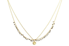 The nkuku Mai Necklace is a delicate layered gold piece with two thin chains—one featuring small pyrite stones and the other holding a round textured gold pendant.